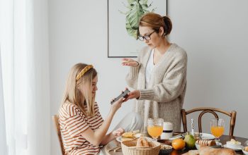 Seorang ibu dan putrinya berdiskusi tentang penggunaan ponsel saat sarapan di rumah.