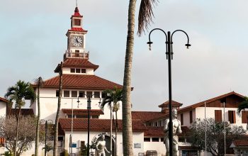 Pemandangan eksterior Perpustakaan Balme di Universitas Ghana dengan pohon palem dan langit yang cerah.