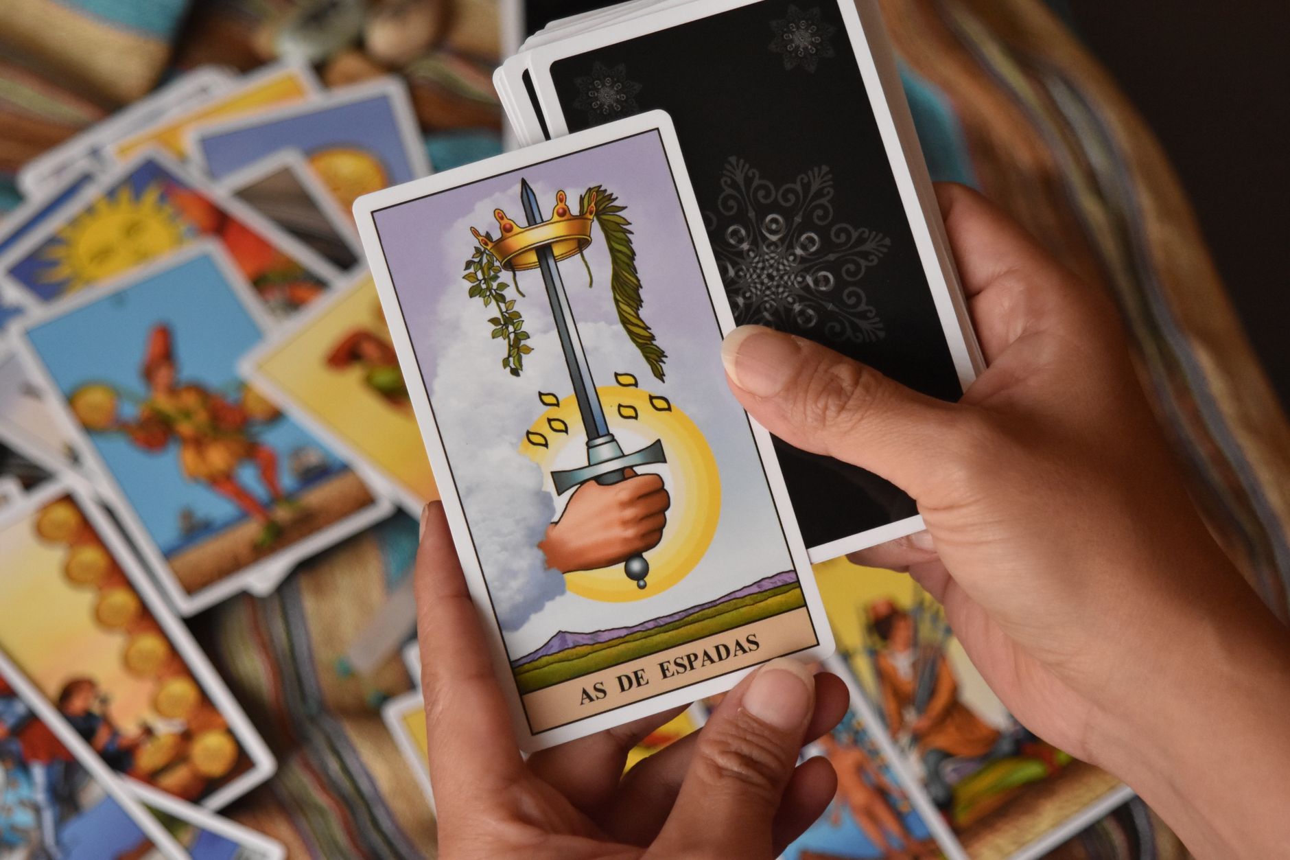 Tampilan dekat tangan yang memegang kartu tarot Ace of Swords selama pembacaan.