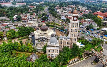Pengambilan gambar udara yang menakjubkan dari sebuah masjid dan menara jam di tengah lanskap perkotaan di Jawa Barat, Indonesia.