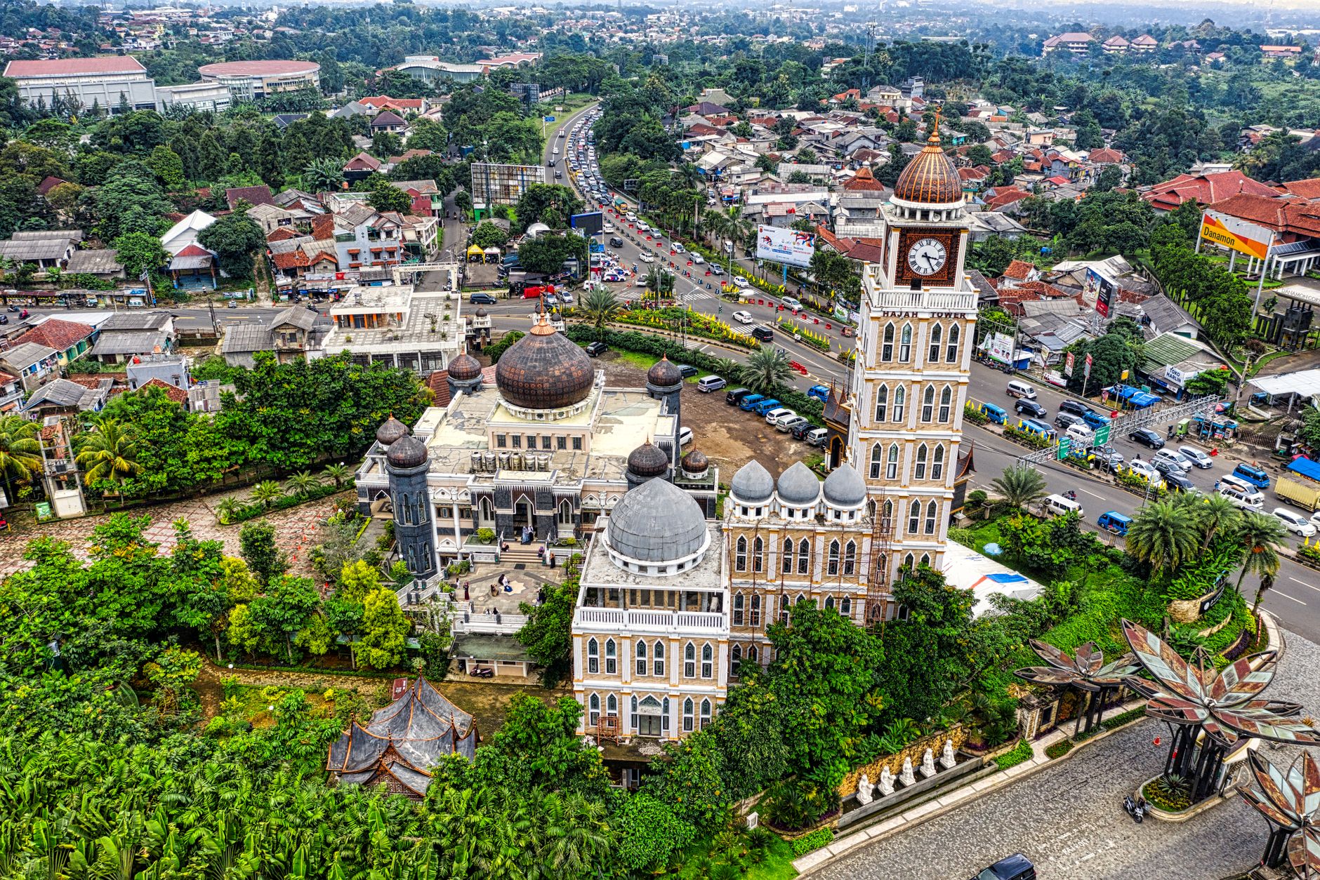 Pengambilan gambar udara yang menakjubkan dari sebuah masjid dan menara jam di tengah lanskap perkotaan di Jawa Barat, Indonesia.