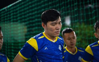 Tim sepak bola Asia berkumpul dalam seragam yang cerah selama pertandingan malam. Fokus pada kerja tim dan sportivitas.