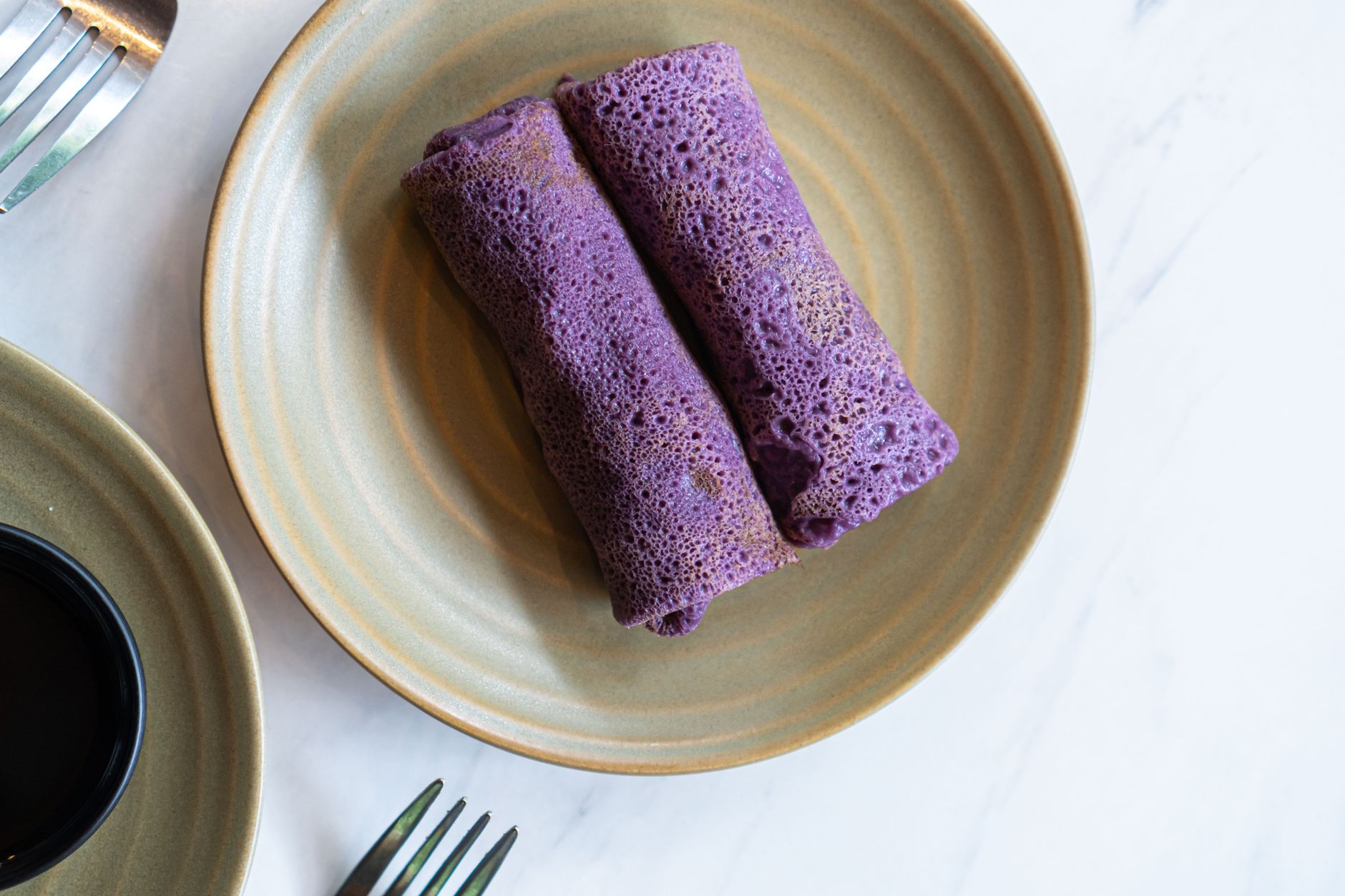 Pancake ungu Indonesia yang lezat (dadar) di piring keramik di Bali, Indonesia.