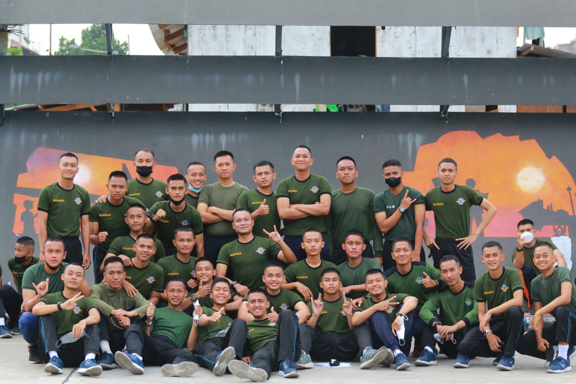 Sekelompok pemuda mengenakan kemeja hijau seragam berpose di luar ruangan di Surabaya, Indonesia.