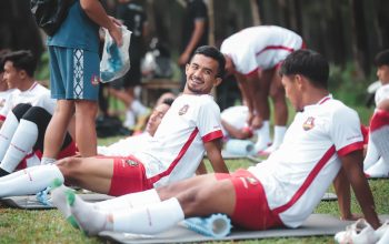 Pemain sepak bola di Jakarta bersantai di atas tikar selama sesi latihan di luar ruangan.